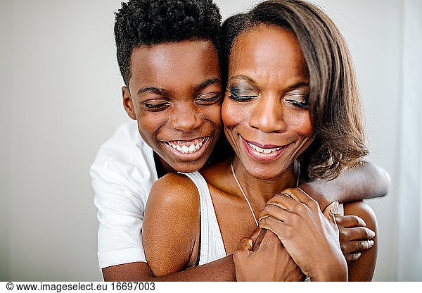 Happy African-American boy hugging mom with closed eyes