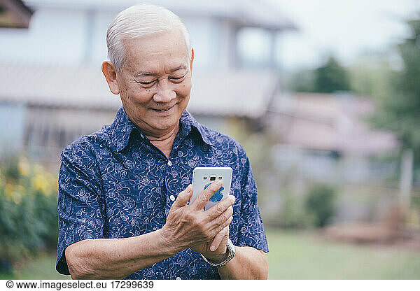 Happy asian elder man using smartphone.