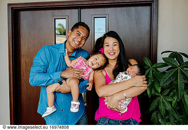 Happy asian family with young daughter and newborn baby