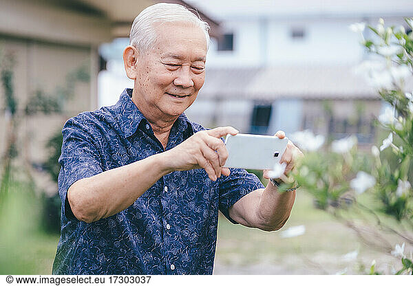 Happy asian senior man taking a picture with mobile phone.
