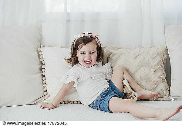 Happy baby girl sitting on sofa in living room