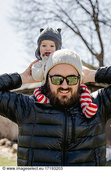 Happy baby on dad's shoulders in backyard on chilly afternoon