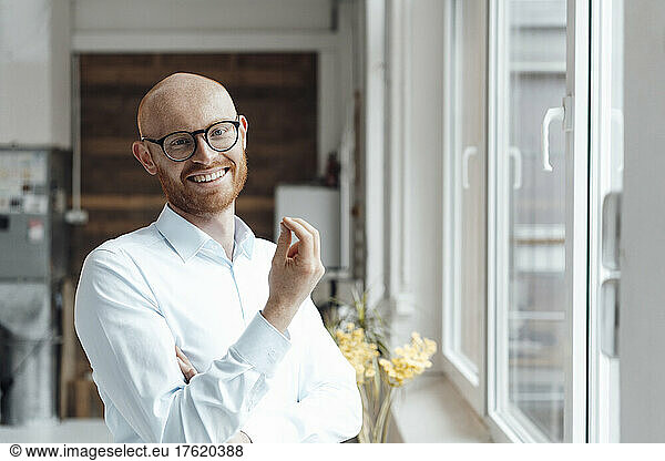 Happy bald working man wearing eyeglasses gesturing in office