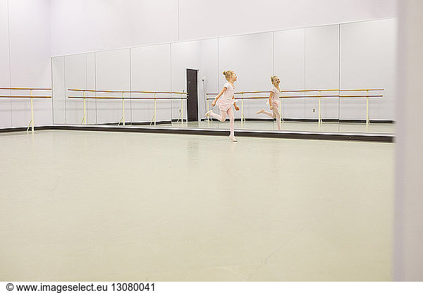 Happy ballet dancer dancing in front of mirror at dance studio