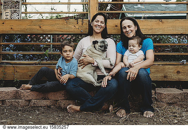 Happy barefoot family with two moms holding boy  baby and Pug