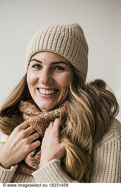 Happy beautiful blond woman wearing warm clothing against white background