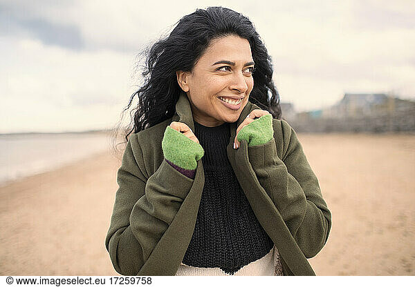 Happy beautiful woman in winter coat on beach