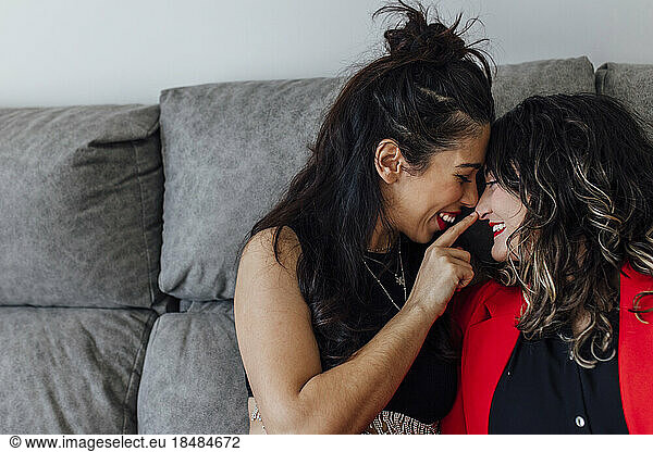 Happy bisexual woman touching girlfriend's nose at home