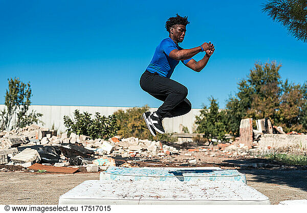 Happy black boy jumping on a mattress.