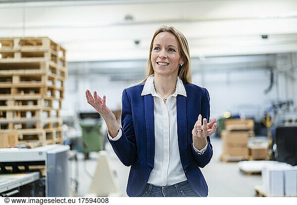 Happy blond businesswoman gesturing in factory