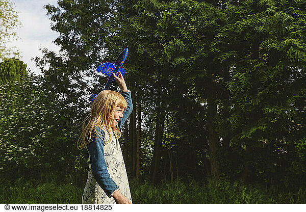 Happy blond girl playing with airplane toy