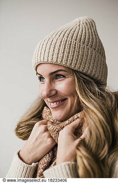 Happy blond woman wearing knit hat against white background