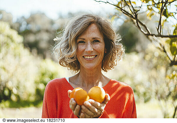 Happy blond woman with organic orange fruits