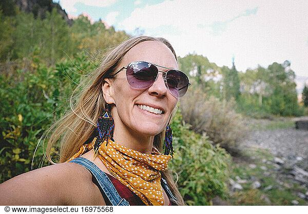 Happy Blonde Woman in Sunglasses Takes Selfie on a Hike