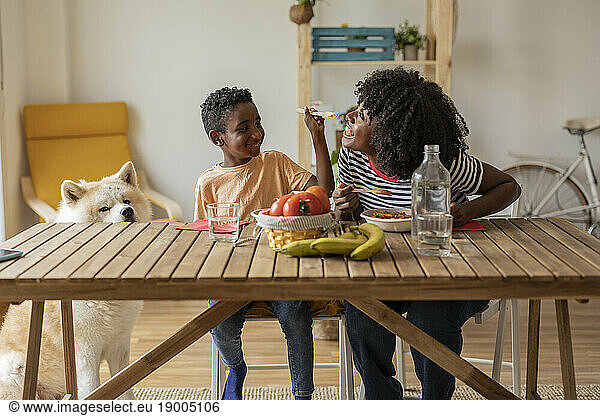 Happy boy feeding mother sitting at dining table