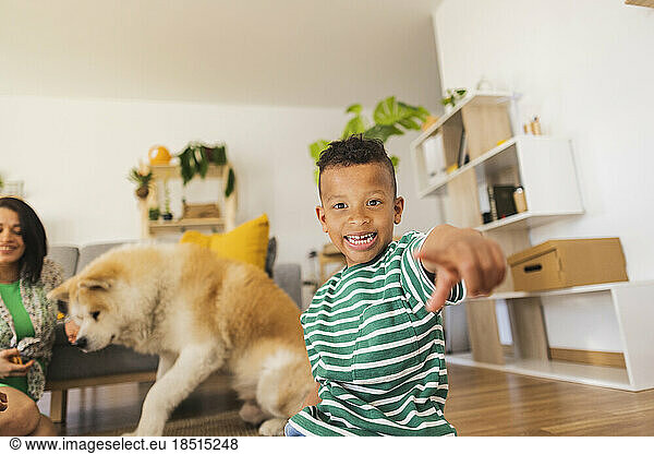 Happy boy gesturing with dog in background at home