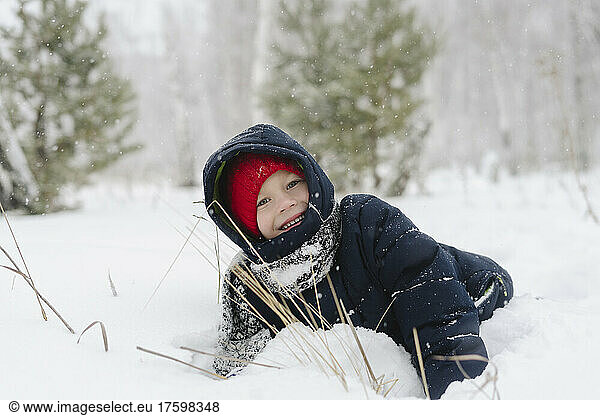 Happy boy playing in snowy forest