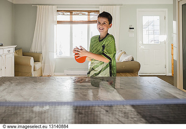 Happy boy playing table tennis at home