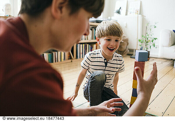 Happy boy playing toy blocks with mother at home