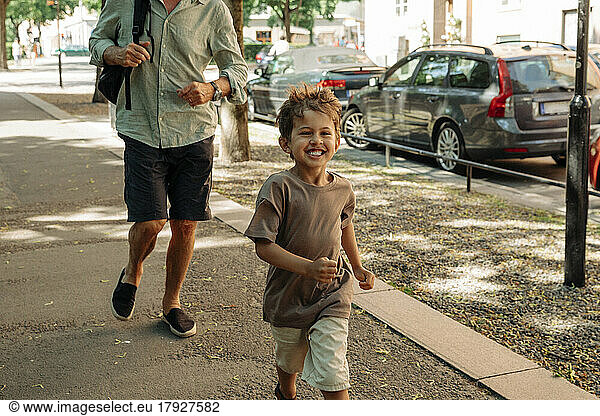Happy boy running with grandfather on sidewalk