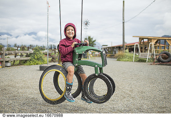 happy boy sits on play ride on tractor made from recycled tires