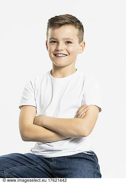 Happy boy sitting with arms crossed at studio