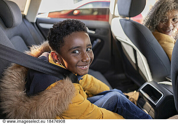 Happy boy sitting with grandmother in car