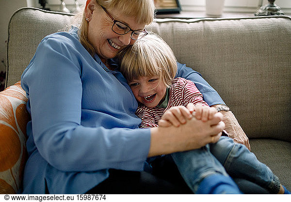 Happy boy sitting with grandmother on sofa at home