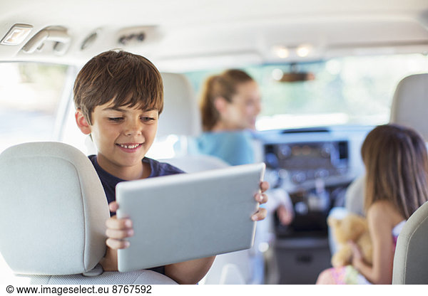 Happy boy using digital tablet in back seat of car