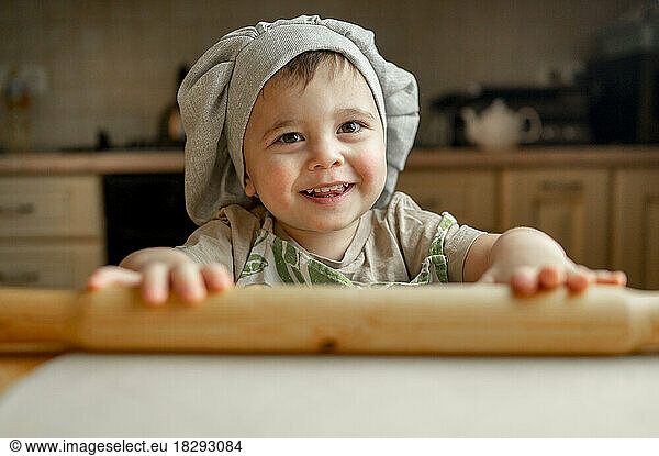 Happy boy wearing chef's hat in kitchen