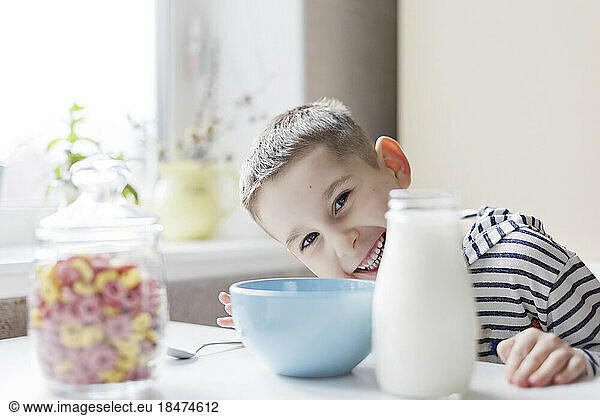 Happy boy with breakfast on table at home