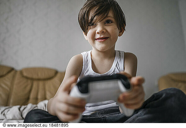 Happy boy with controller playing video games at home