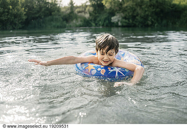 Happy boy with inflatable swim ring swimming in water
