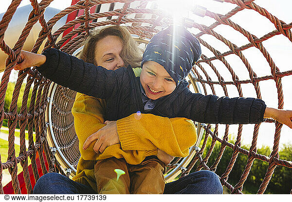 Happy boy with mother playing in jungle gym at playground