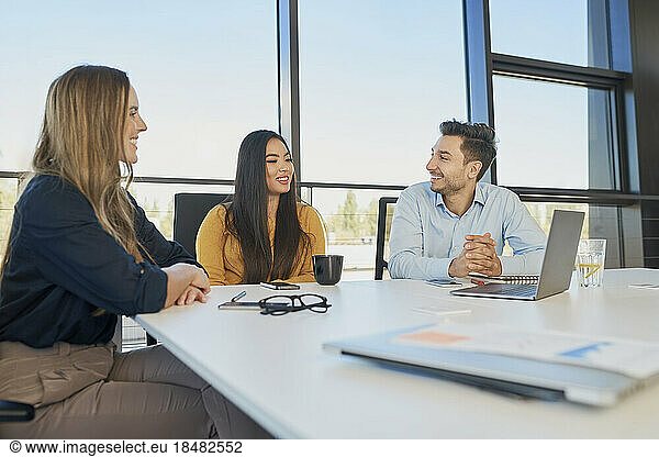 Happy business colleagues planning strategy sitting at desk in workplace