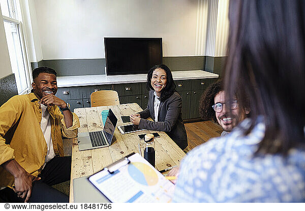 Happy business colleagues sitting at desk in office meeting