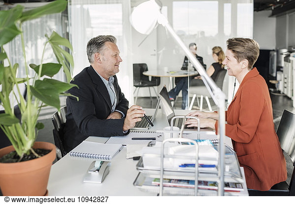 Happy business people having discussion at desk