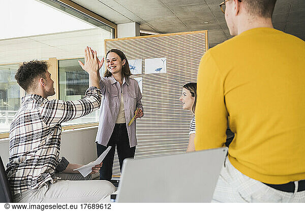 Happy business people high fiving in office