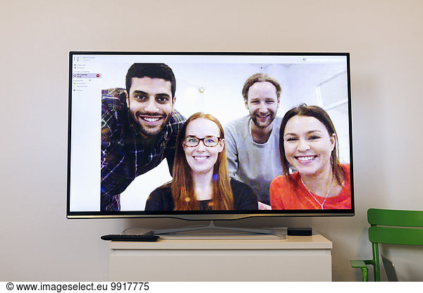 Happy business people on screen in video conference room at creative office