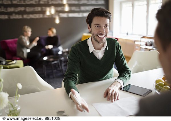 Happy businessman discussing with colleague at office desk