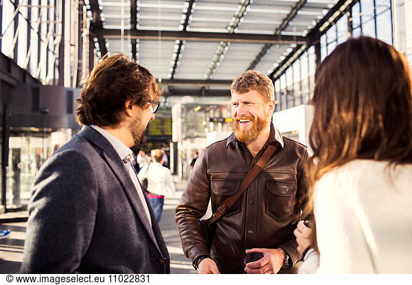 Happy businessman discussing with colleagues at railroad station