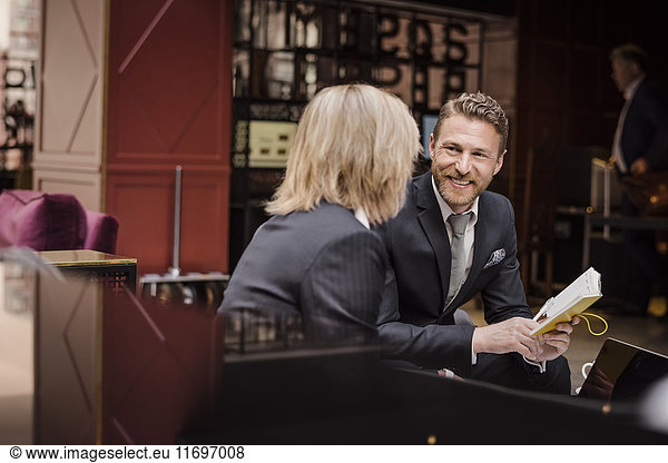 Happy businessman looking at female partner during meeting in hotel reception