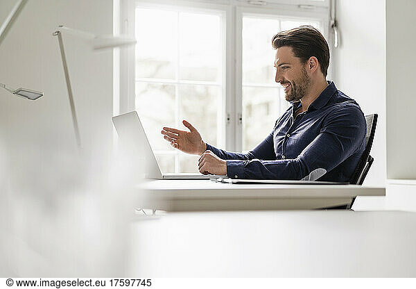 Happy businessman on video call through laptop at office
