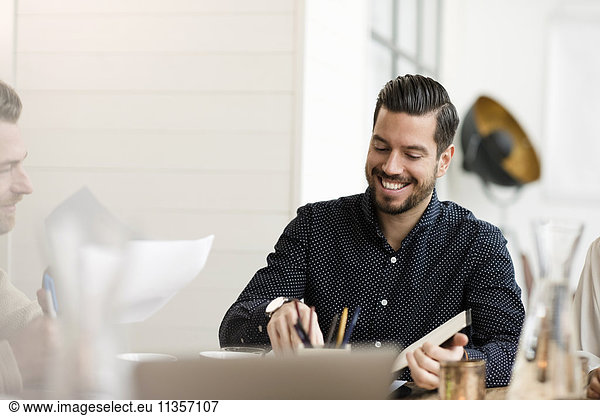 Happy businessman reading document while sitting at table in office