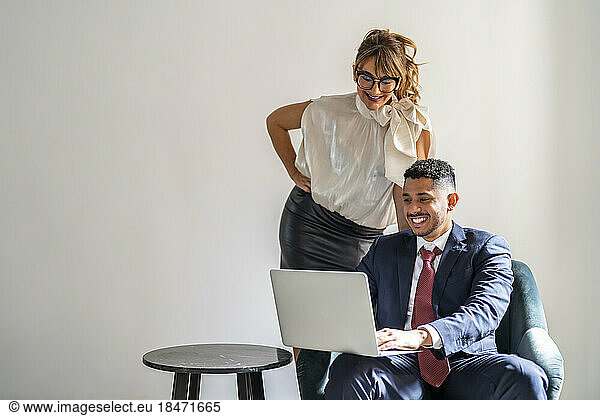 Happy businessman sharing laptop with colleague
