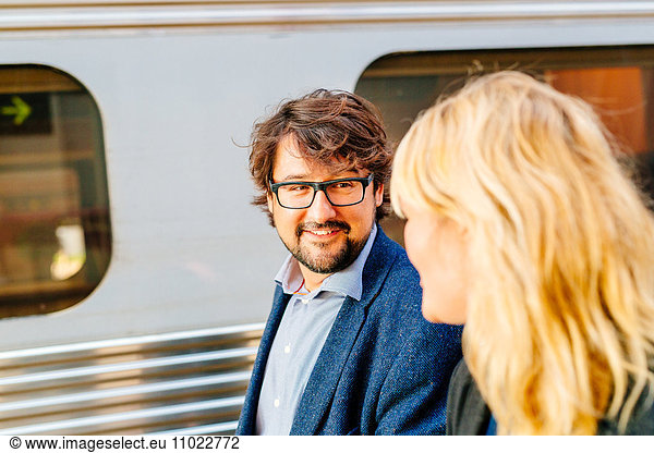 Happy businessman talking to female colleague at railroad station