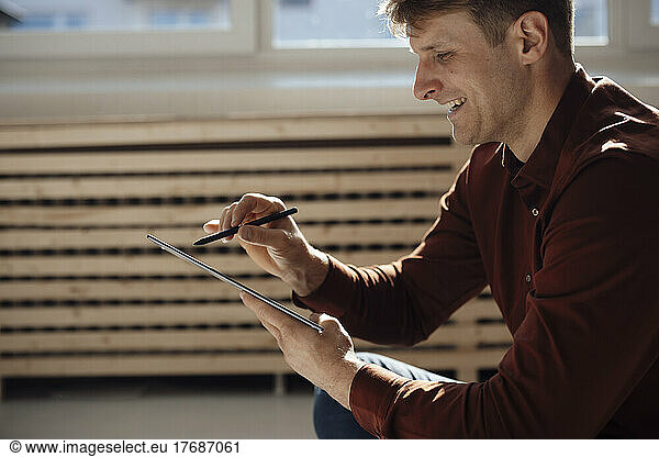 Happy businessman using tablet PC with digitized pen in office