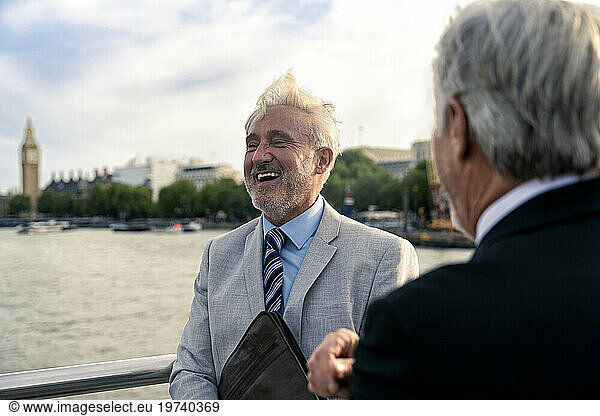 Happy businessman with colleague in front of Thames river