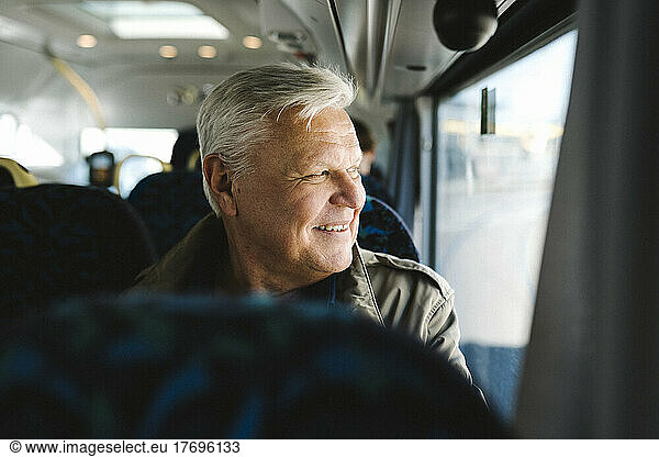 Happy businessman with gray hair looking through bus window