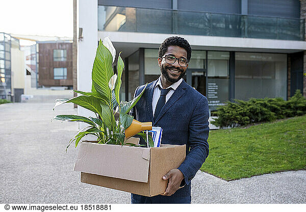 Happy businessman with his belongings leaving office building